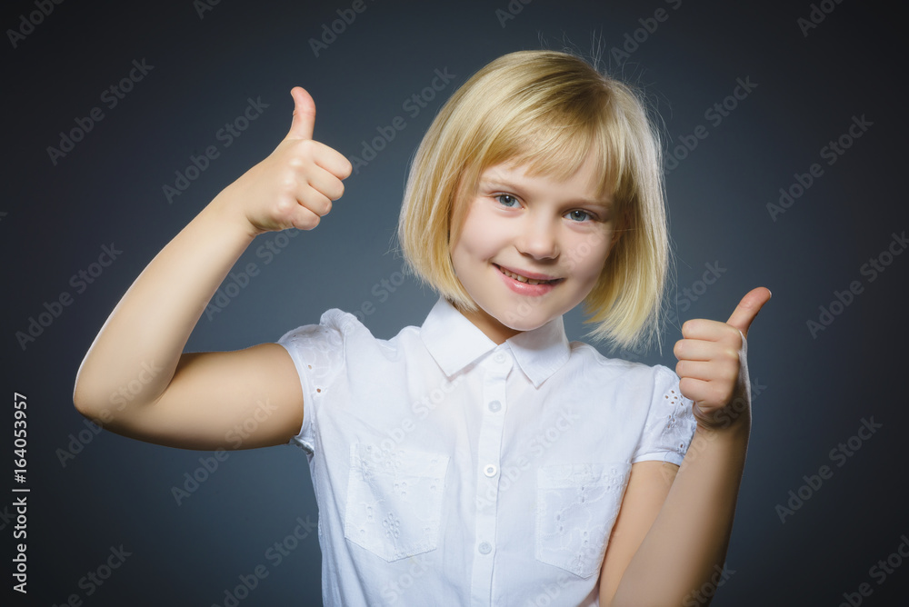 Happy girl showing thubs up. Closeup Portrait child smiling isolated on grey Happy girl showing thubs up. Closeup Portrait child smiling isolated on grey