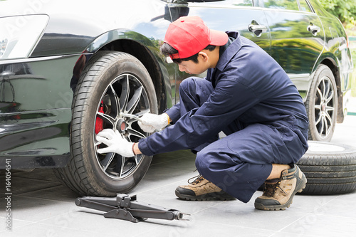 Mechanic replacing lug nuts changing tires on vehicle