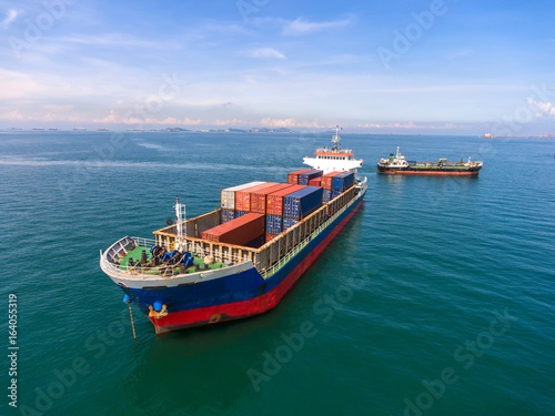 container ship in import export and business logistic.By crane , Trade Port , Shipping.Tugboat assisting cargo to harbor.Aerial view. Top view.