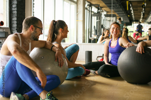 Group of people workout in healthy club. People having conversation after Pilates exercise with Pilates ball.