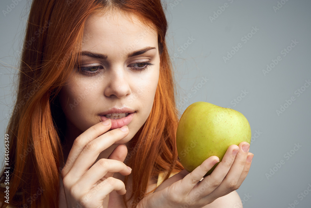 Beautiful young woman on a gray background holding an apple Beautiful young woman on a gray background holding an apple