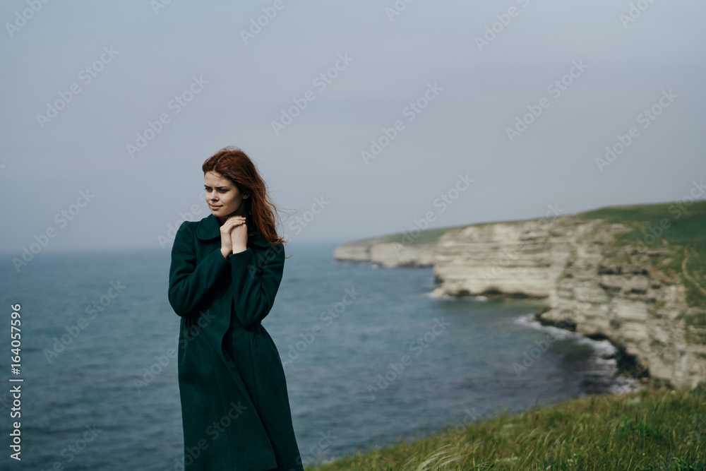 Beautiful young woman on a cliff of a mountain near the sea