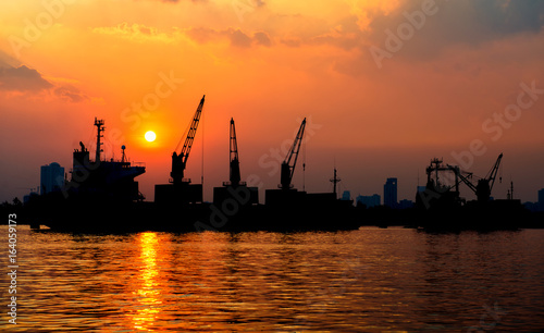 container ship in import export and business logistic.By crane , Trade Port , Shipping.Tugboat assisting cargo to harbor.Aerial view. Top view.Silhouette.