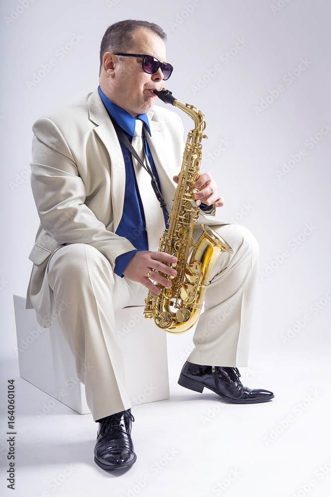 Fototapeta premium Saxophone only. Saxophonist. Caucasian man with a saxophone. Dressed in a white suit. The studio silhouette on a white background.
