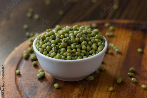 Organic mung beans on white ceramic bowl over wooden background.