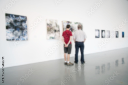 Blurry background of art gallery with people pay attention with the image on the wall.