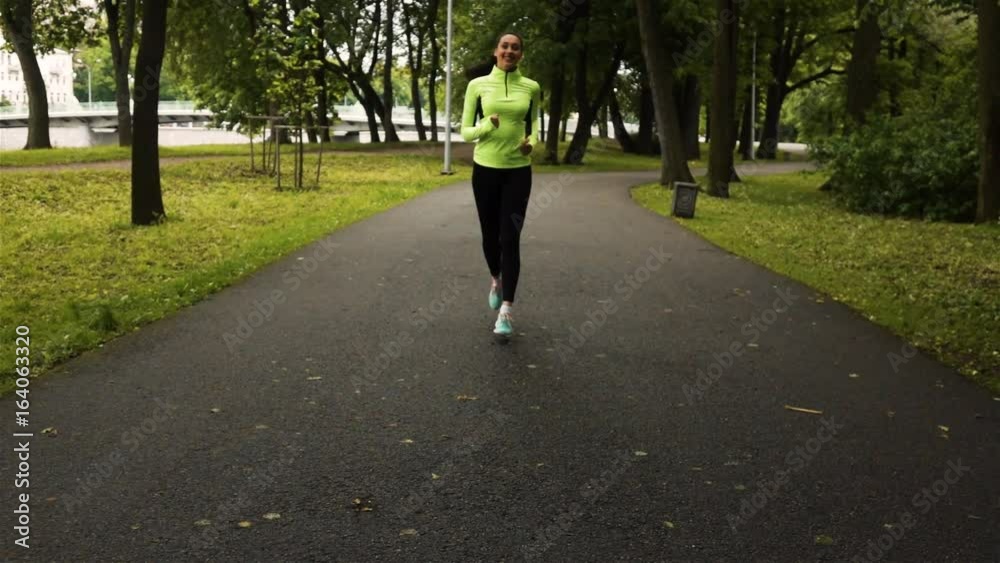 Sport woman running in park exercising outdoors. Front wide view super slow motion high speed camera steadicam footage Sport woman running in park exercising outdoors. Front wide view super slow motion high speed camera steadicam footage