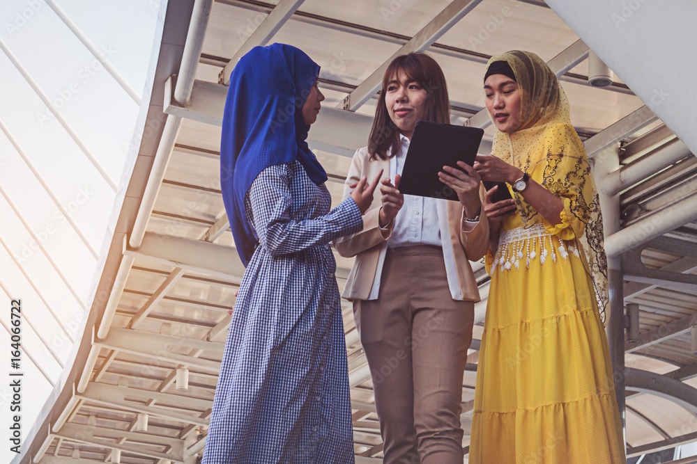 Muslim women messaging on a tablet in the city.