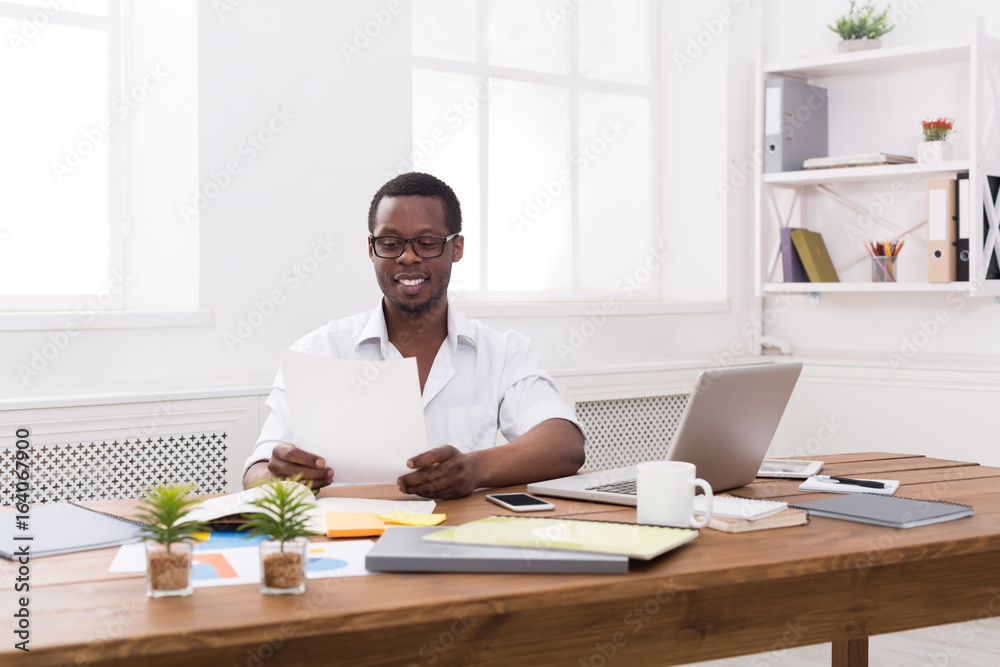 Young black businessman working with papers in modern white office Young black businessman working with papers in modern white office