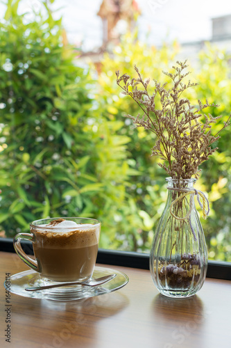 Cappuccino cup of coffee with vase on wooden table