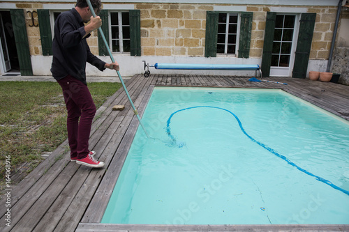 Man cleaning the swimming pool with vacuum cleaner