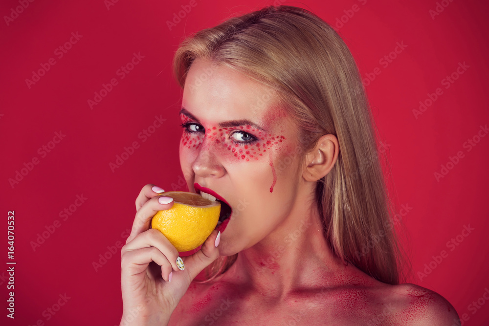young girl bite yellow lemon on red background young girl bite yellow lemon on red background