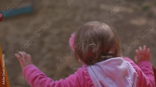 Little two year old blond girl in jeans plays in a children's park, children slide photo