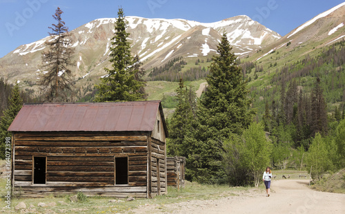 A Woman Walks by an Old Cabin on the Alpine Loop Backcountry Byway