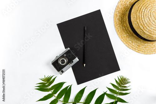 Straw hat with green leaves and old camera on white background, Summer background. Top view photo