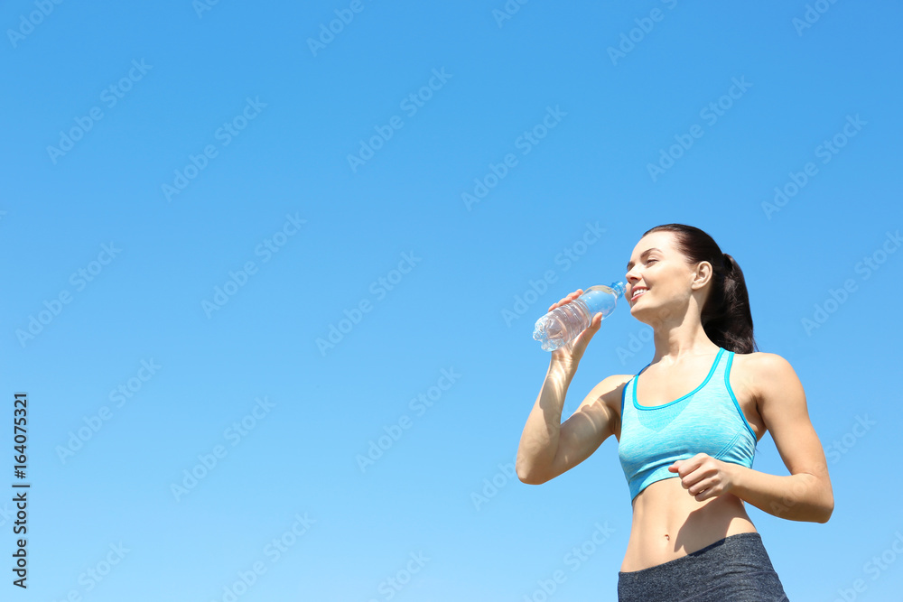 Sporty woman drinking water after jogging outdoors Sporty woman drinking water after jogging outdoors