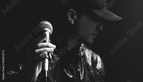 asian male singer hands on microphone, black and white photo