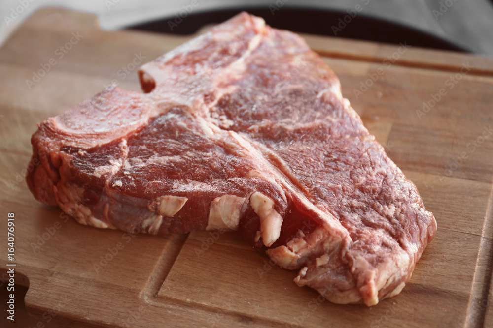 Fresh raw beefsteak on wooden board, closeup Fresh raw beefsteak on wooden board, closeup
