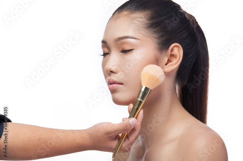 Portrait of a beautiful young woman, Close up of hand of make-up artist applying powder on female face, beauty asia photo