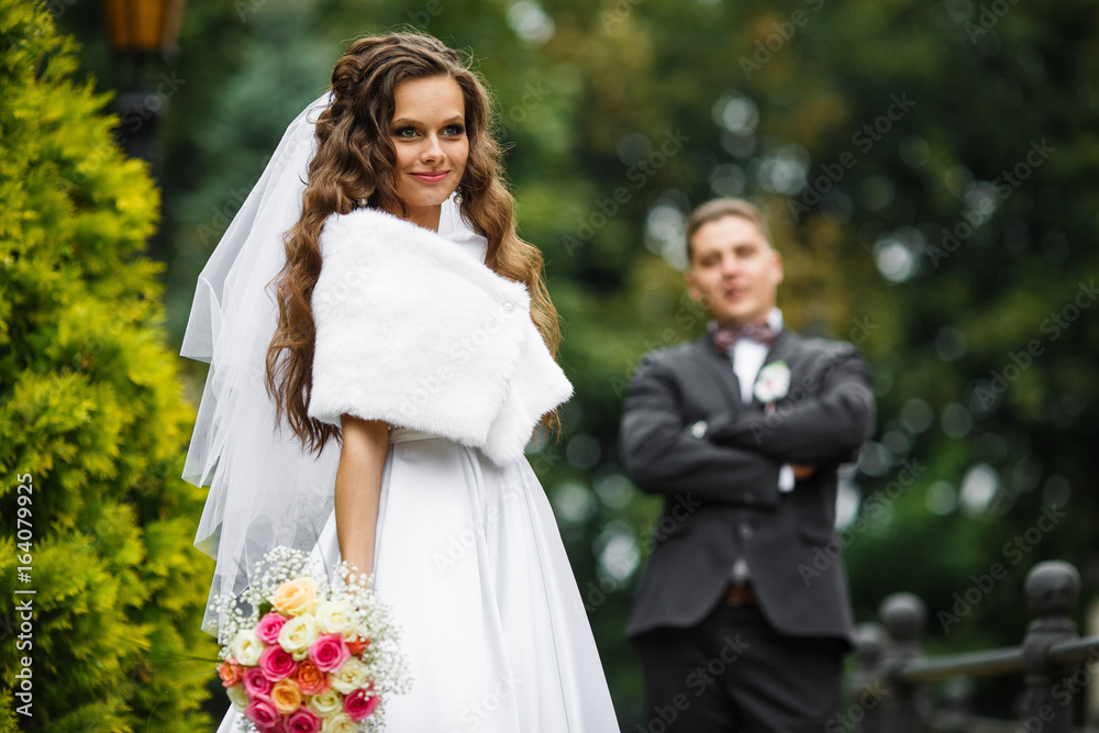 Obraz premium Groom looks with love at bride posing outside