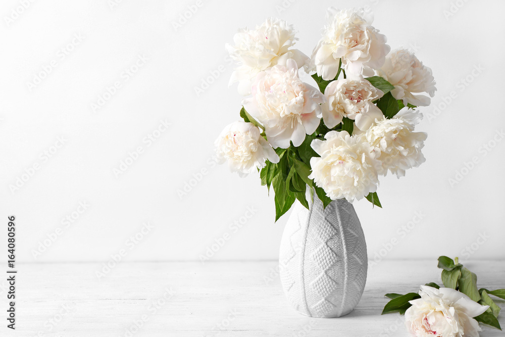 Vase with beautiful peonies on white background