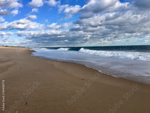 Beautiful empty sand beach with surfer waves and a blue sky with white clouds in Charlestown, Rhode Island (United States of America)