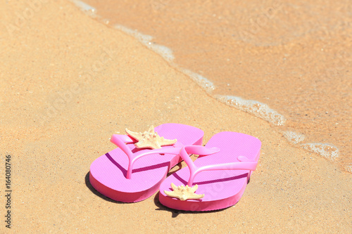 Colorful flip-flops and starfish on sand at sea shore. Vacation concept