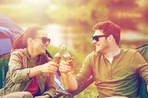 happy couple clinking drinks at campsite tent
