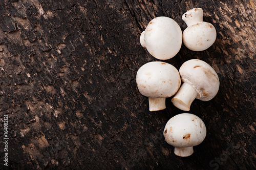 Mushrooms champignons on an old wooden background.