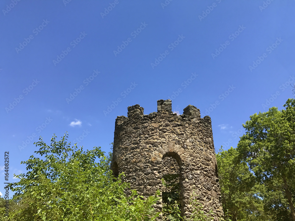 Tower of an ancient fortress. Abandoned old castle tower on the background of blue sky. Copy space for your text