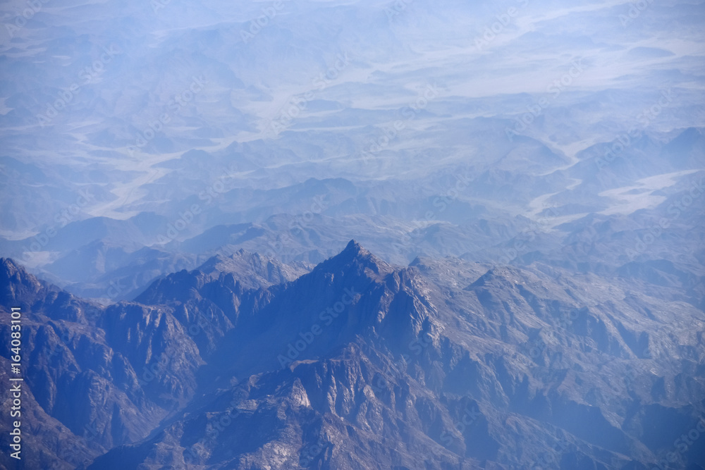 Peaks of mountains high in sky from airplane flight