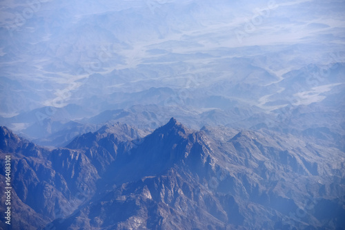 Peaks of mountains high in sky from airplane flight