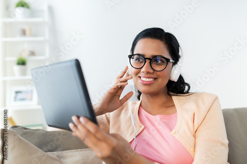 happy woman with tablet pc and headphones at home