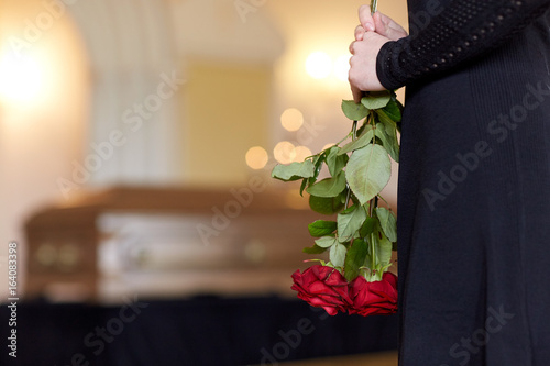 close up of woman with roses and coffin at funeral