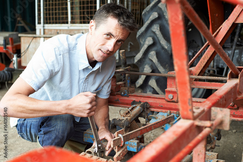 Farmer Working On Agricultural Equipment In Barn