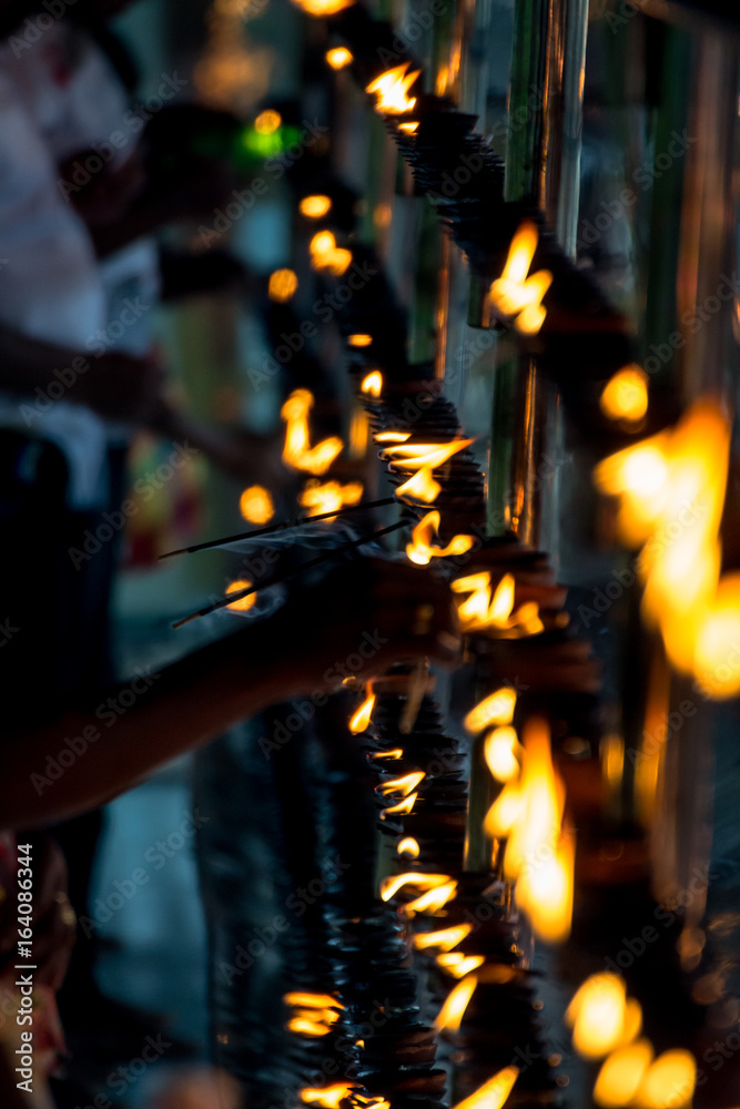 Detail of buddhist prayers setting candles in fire