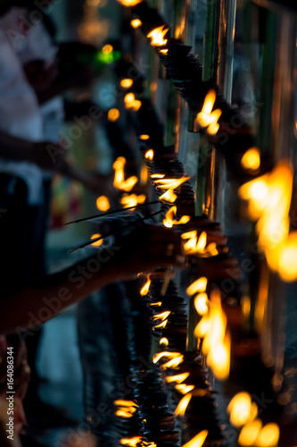 Detail of buddhist prayers setting candles in fire