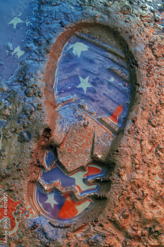 Reflection of the American flag on the footprint of the boot in the ground