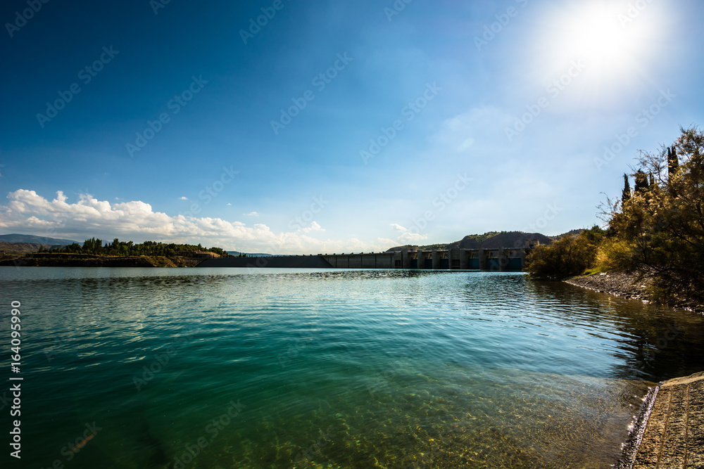 Shore of a calm reservoir near the dam