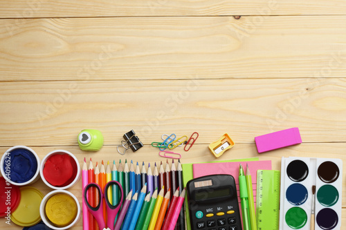 school and office supplies. school background. colored pencils, pen, pains, paper for school and student education on wooden background. top view with copy space