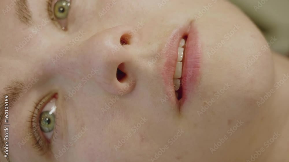 Close up of girl's face while being tattooed. Girl closes her eyes and looks aside bearing pain. Slow motion Close up of girl's face while being tattooed. Girl closes her eyes and looks aside bearing pain. Slow motion