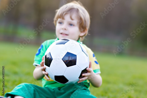 Little cute kid boy of 4 playing soccer with football on field, outdoors © Irina Schmidt
