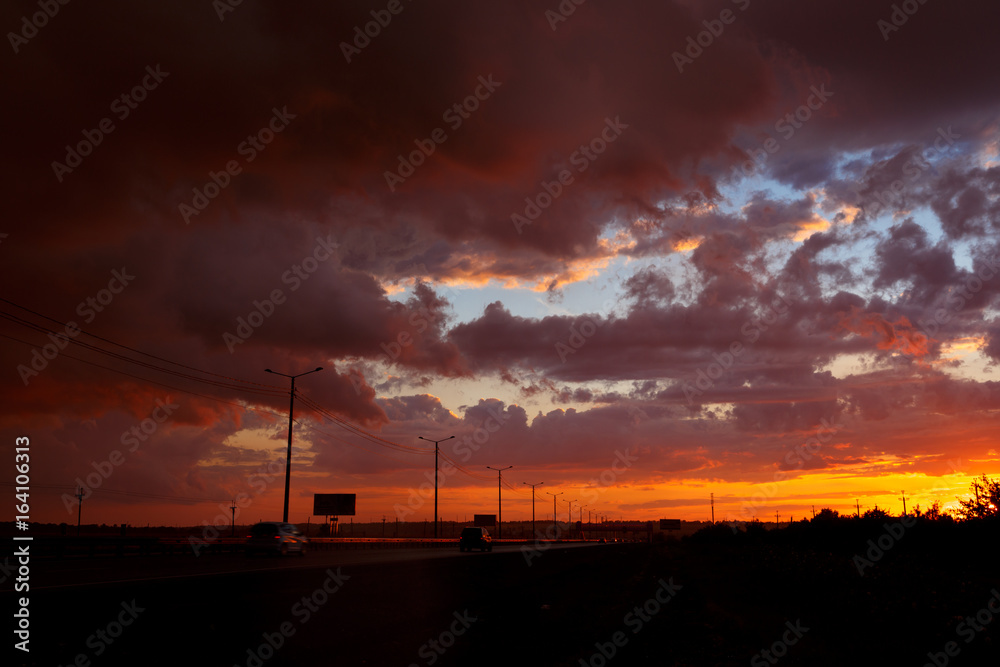 Beautiful sunset landscape with cars on the road.