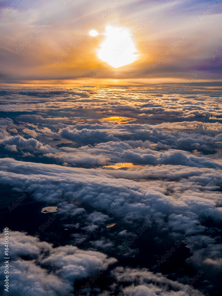 Dramatic clouds in sunset sky from the view of an airplane window.