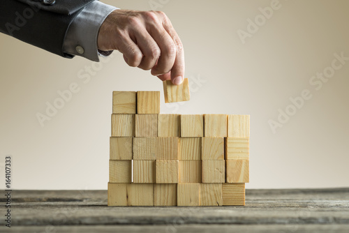 Businessman building a structure with wooden cubes on table surface