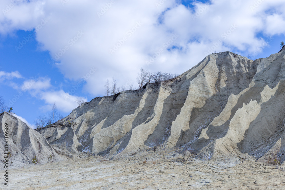 Sand hills with blue sky clouds. Mountain in the abandoned mines. Quarry and old prison architecture. The ashes dunes in Estonia, Europe.