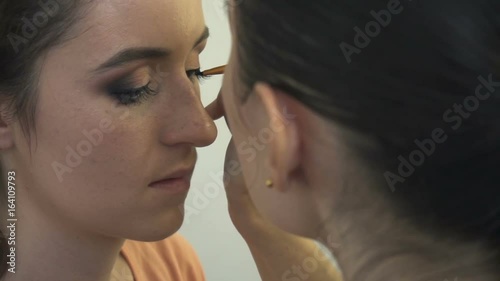 Make-up artist makes a professional make-up for a beautiful girl