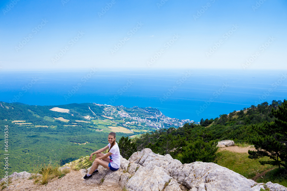 Naklejka premium Young traveler on a mountain peak with sea and blue sky on Background