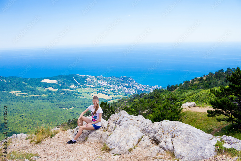 Young traveler on a mountain peak with sea and blue sky on Background