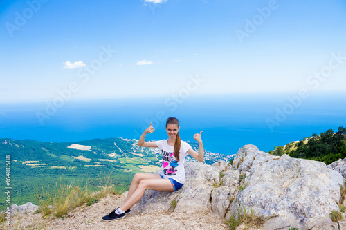 Young traveler on a mountain peak with sea and blue sky on Background